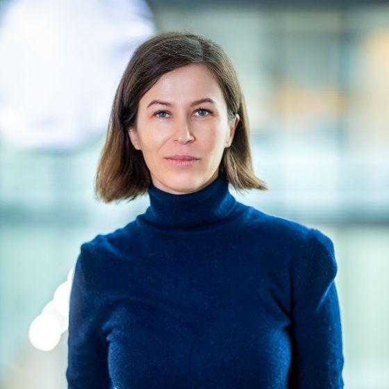 Become a member of Mautic 4 Photo of a woman with shoulder-length dark hair wearing a dark blue polar neck jumper.