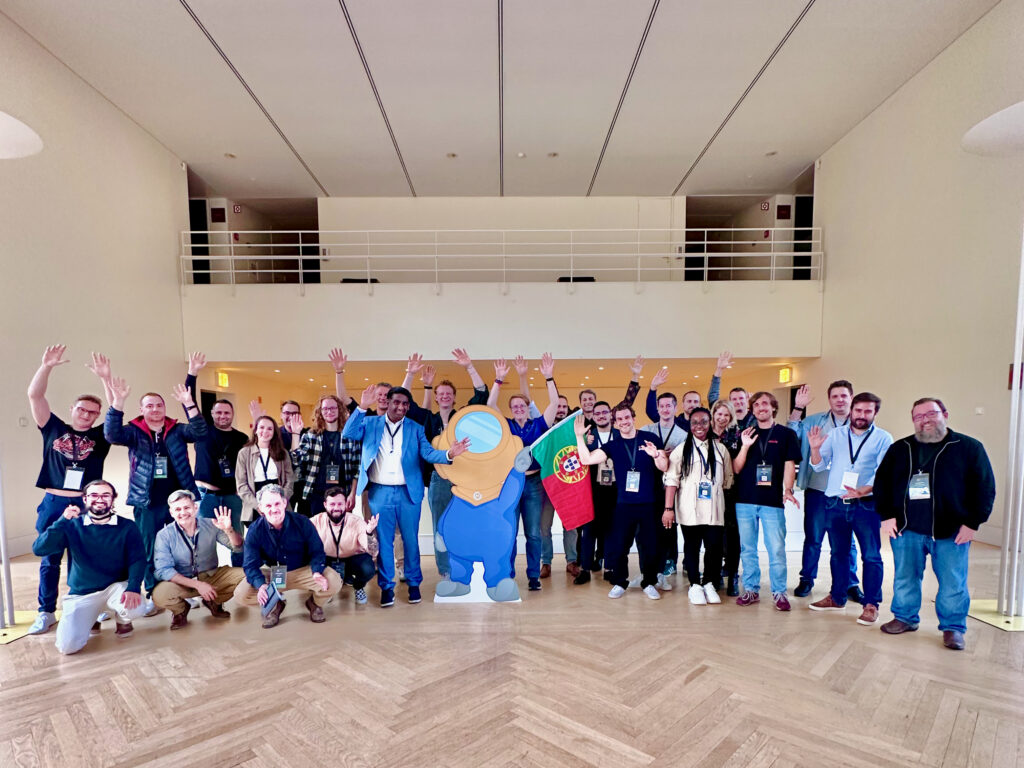 2024: year in review 4 Photo of lots of Mauticians standing around a cardboard cutout of the Mautinaut holding a Portugal flag.