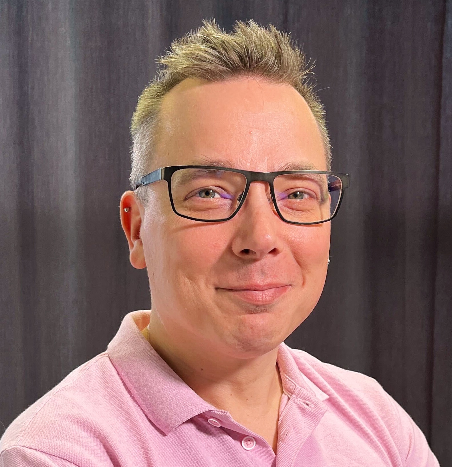Become a member of Mautic 5 Photo of a white man wearing glasses with short fair hair spiked at the front. He's wearing a pink collared shirt with the top buttons undone.