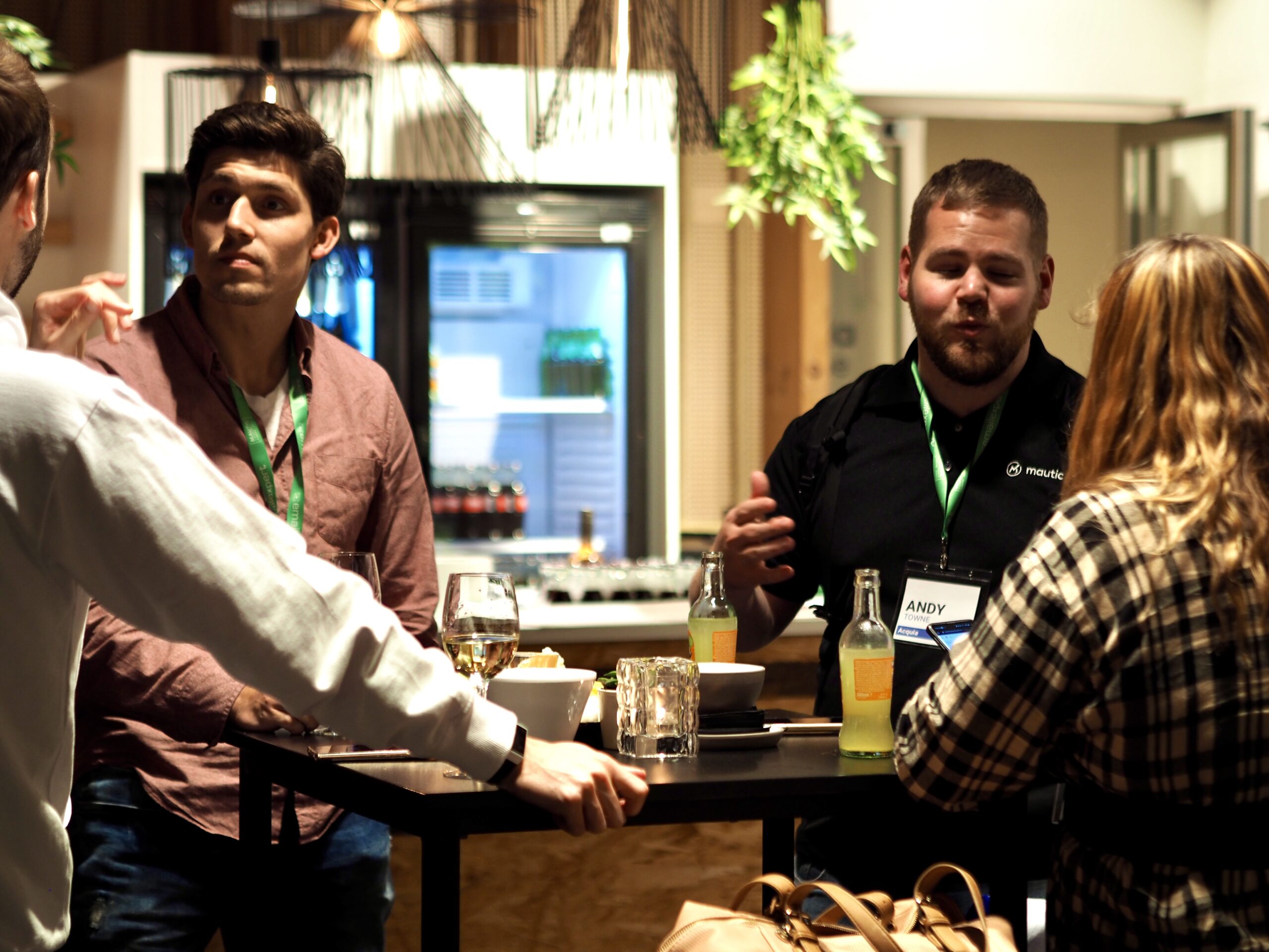 Become a member of Mautic 1 Photo of four people standing around a table at a conference talking.